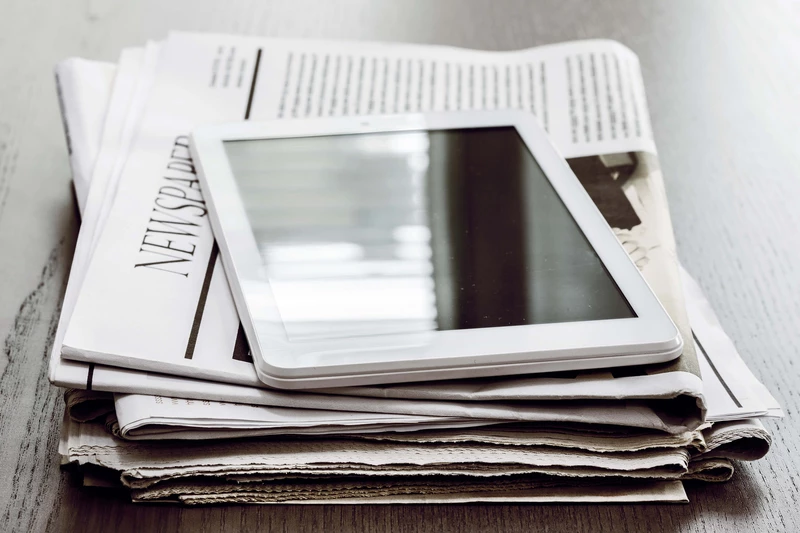Tablet lying on a pile of newspapers